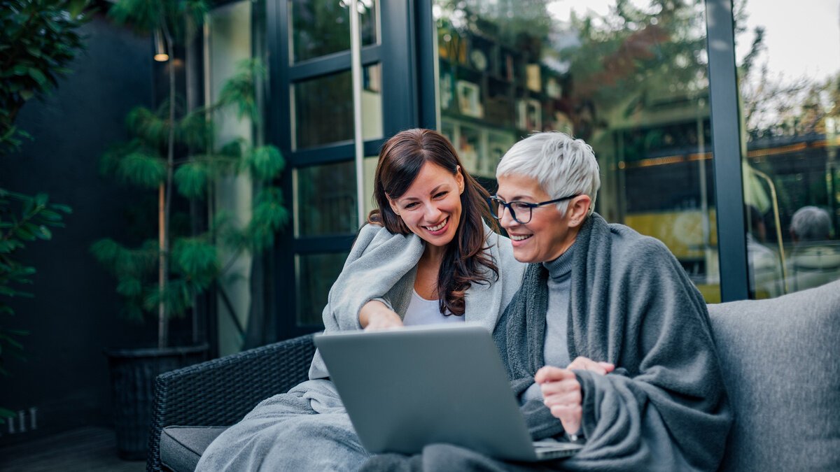 Altersarmut ist weiblich - 2 Frauen unterschiedlicher Generationen glücklich zusammen auf einer Terrasse