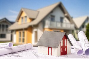 Bauturbo - Bauplan mit Modellhaus und echtem Einfamilienhaus im Hintergrund