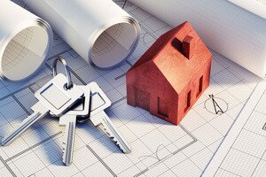 Grundbuch - Person am Schreibtisch mit Schlüssel, Notizen, Modellhaus