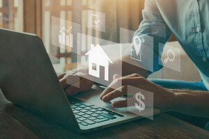 Grunderwerbsteuer - Person am Laptop mit eingeblendeten Grafiken