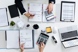 Grunderwerbsteuer Sparen - Schreibtisch mit Notizen und Taschenrechnern von oben