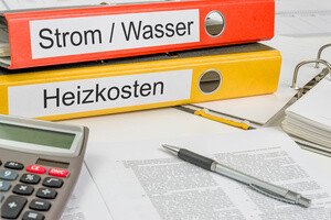 Haus dämmen - Schreibtisch mit Ordnern zum Thema Strom-, Wasser-, Heizkosten