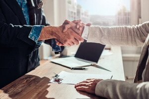 Immobilien Teilverkauf - Transparenz - Hände Schütteln über dem Schreibtisch