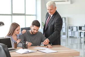 Immobilienmakler Ausbildung - Makler berät Paar am Schreibtisch