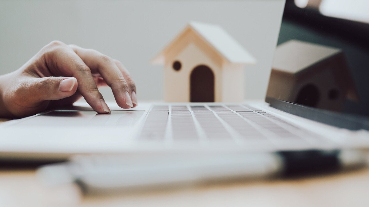 Kapitalanlage Pflegeimmobilien - Büro Laptoptastatur mit Modellhaus im Hintergrund