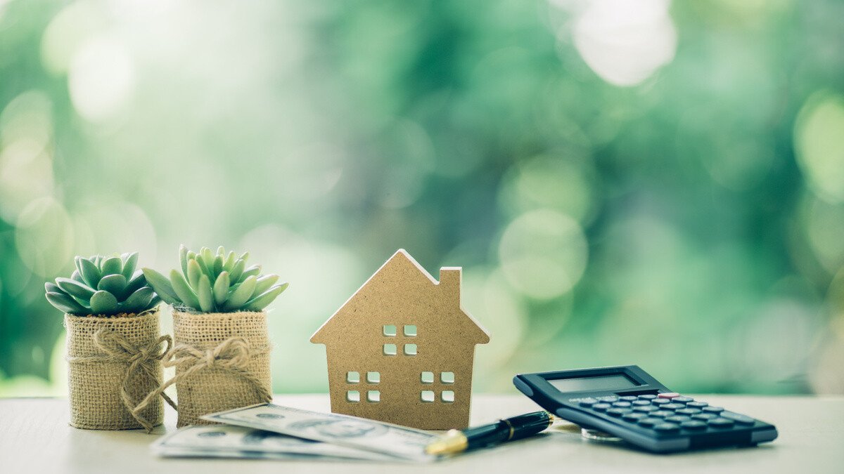 Regulierung Teilverkauf - Modellhaus, Geldscheine und Taschenrechner auf einem Tisch