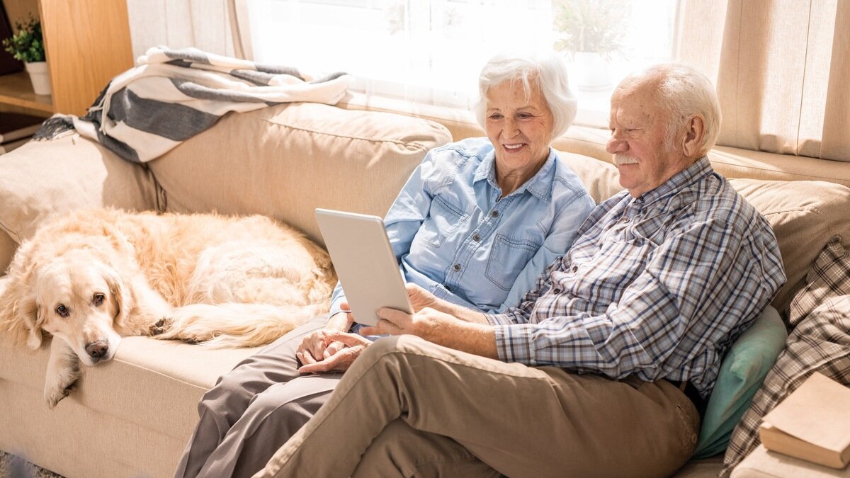 Seniorenfinanzierung - älteres Ehepaar mit Hund auf der Couch
