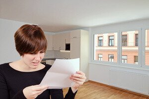 Versicherungen fuer Mieter - Mieterin in der Wohnung liest ein Schreiben