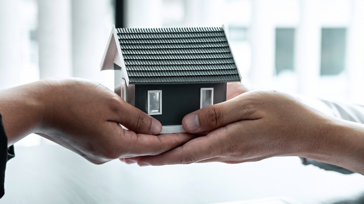 Wertermittlung Immobilie Schenkung - 2 offene Handflächen mit einem Modellhaus darauf