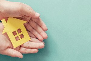 Wertermittlung Immobilie Schenkung - 2 offene Handflächen mit einem gelben Modellhaus darauf