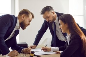 Änderung der Teilungserklärung - 3 Anwälte über einen Schreibtisch gebeugt im Gespräch