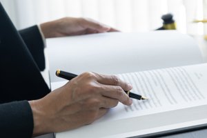 Änderung der Teilungserklärung - Person liest ein Buch am Schreibtisch - Nahaufnahme