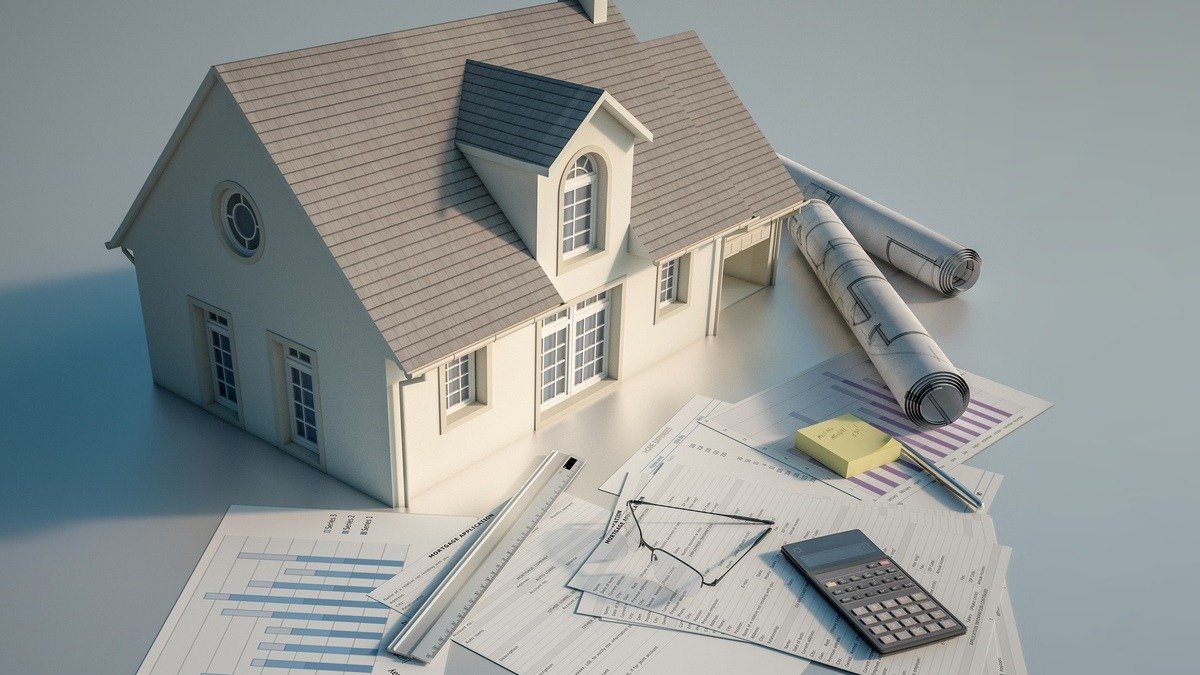 Bauzinsen-2026 - Modellhaus neben Bauunterlagen und Taschenrechner