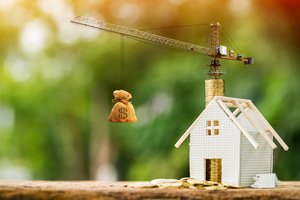 Bauzinsen-2026 - Modellhaus mit Modellkran mit Geldsack