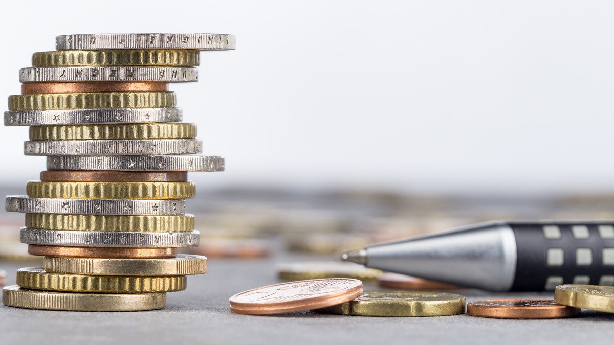 Bonitätsprüfung - Münzstapel mit Kugelschreiber als Finanzsymbol