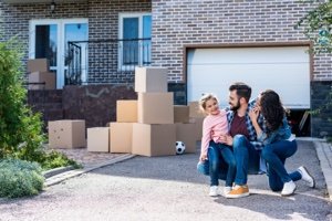 Familie mit Umzugskartons vor einem Haus als Symbol für Eigentümer und Erben