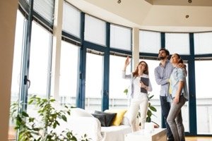 Erbteil verkaufen - Maklerin zeigt jungem Paar helle Wohnung bei Besichtigung