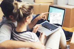 ETF-Sparplan - junges Paar am Laptop zwischen Umzugskartons