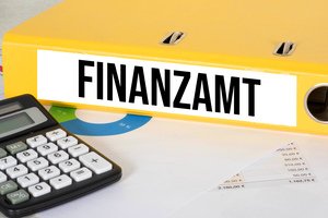 Familienheim erben - Gelber Ordner mit Schriftzug Finanzamt neben Taschenrechner