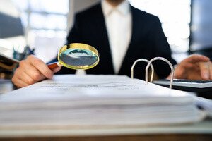 Gesetzentwürfe aus Berlin - aufgeschlagener Ordner wird mit der Lupa betrachtet