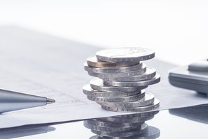 Euro-Münzen neben Taschenrechner und Unterlagen