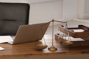 Immobilienteilverkauf - Waage, Stempel, Laptop auf dem Schreibtisch eines Anwalts