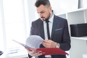 Immobilienteilverkauf - Anwalt in einem hellen Büro schaut auf eine Mappe