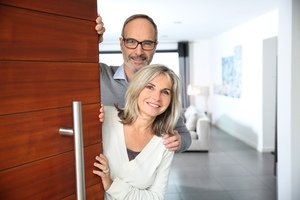 Immobilienteilverkauf - älteres Paar öffnet die Wohnungstür für Besuch