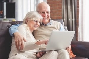 Immobilienteilverkauf Marktupdate 2026 - Seniorenpaar sitzt zufrieden mit Laptop auf dem Sofa