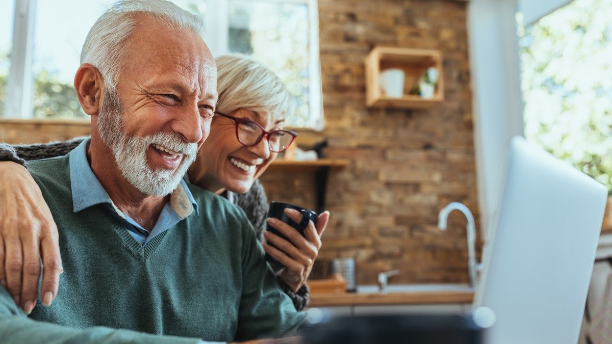 Immobilienverrentung - Seniorenpaar lÃ¤chelt gemeinsam vor einem Computerbildschirm
