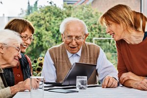Immobilienverrentung - Seniorengruppe lernt gemeinsam mit Tablet am Tisch