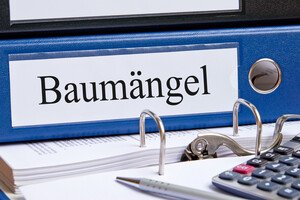 Mietminderung wegen Mängeln - Aktenordner mit Beschriftung Baumängel neben Taschenrechner