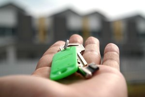 Hand hält Schlüssel vor Wohnhäusern