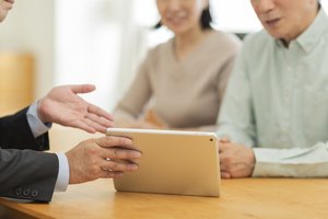 steigende_pflegekosten - Berater zeigt Seniorenpaar ein Tablet im Gespräch